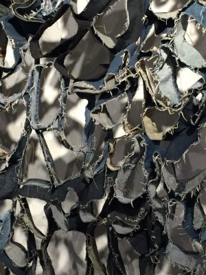 A close-up: "Sifuentes, who is of Korean origin and the daughter of a seamstress, gathers stories along with these textile scraps, the remnants of blue jeans, a garment inextricably linked to American identity. Calling her final pieces 'quilts,' Sifuentes challenges expectations further. While quilts are typically made by sewing a layer o batting between a top and bottom layer, here Sifuentes uses gaps - perhaps a metaphor for untold stories - as a middle layer."